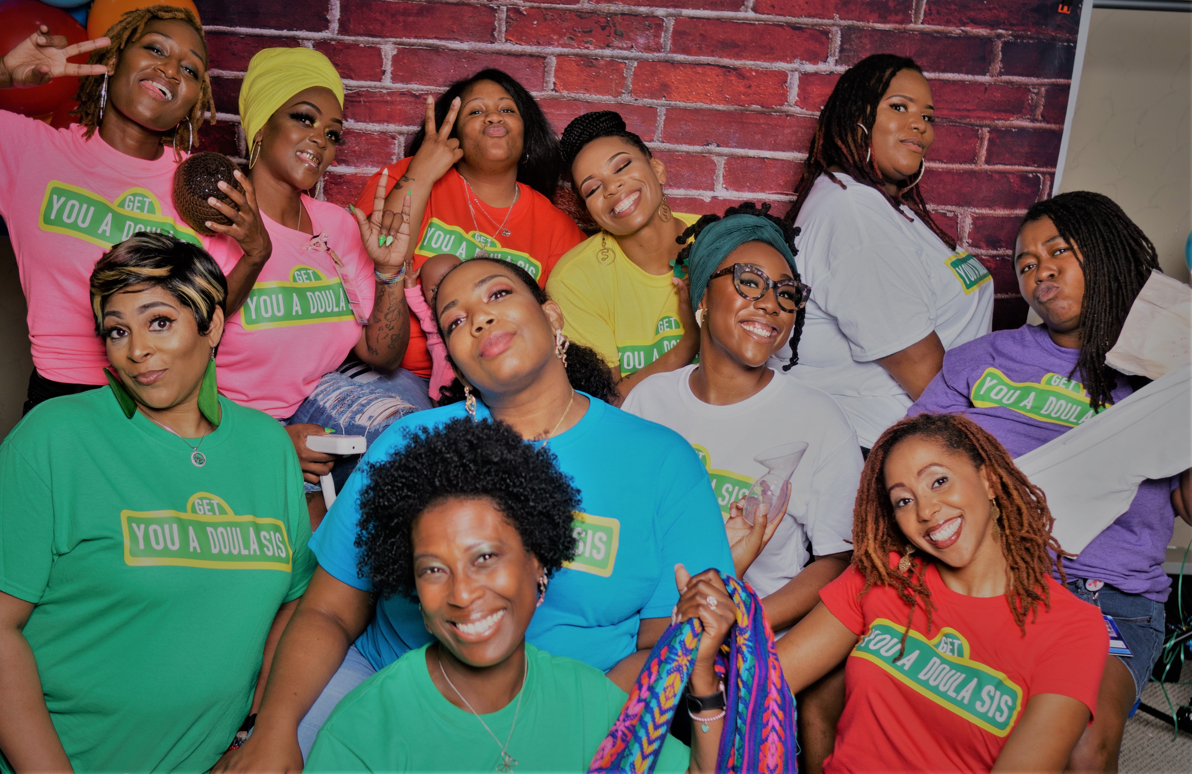 Doula Lab community members wearing 'Get You a Doula Sis' shirts, smiling together